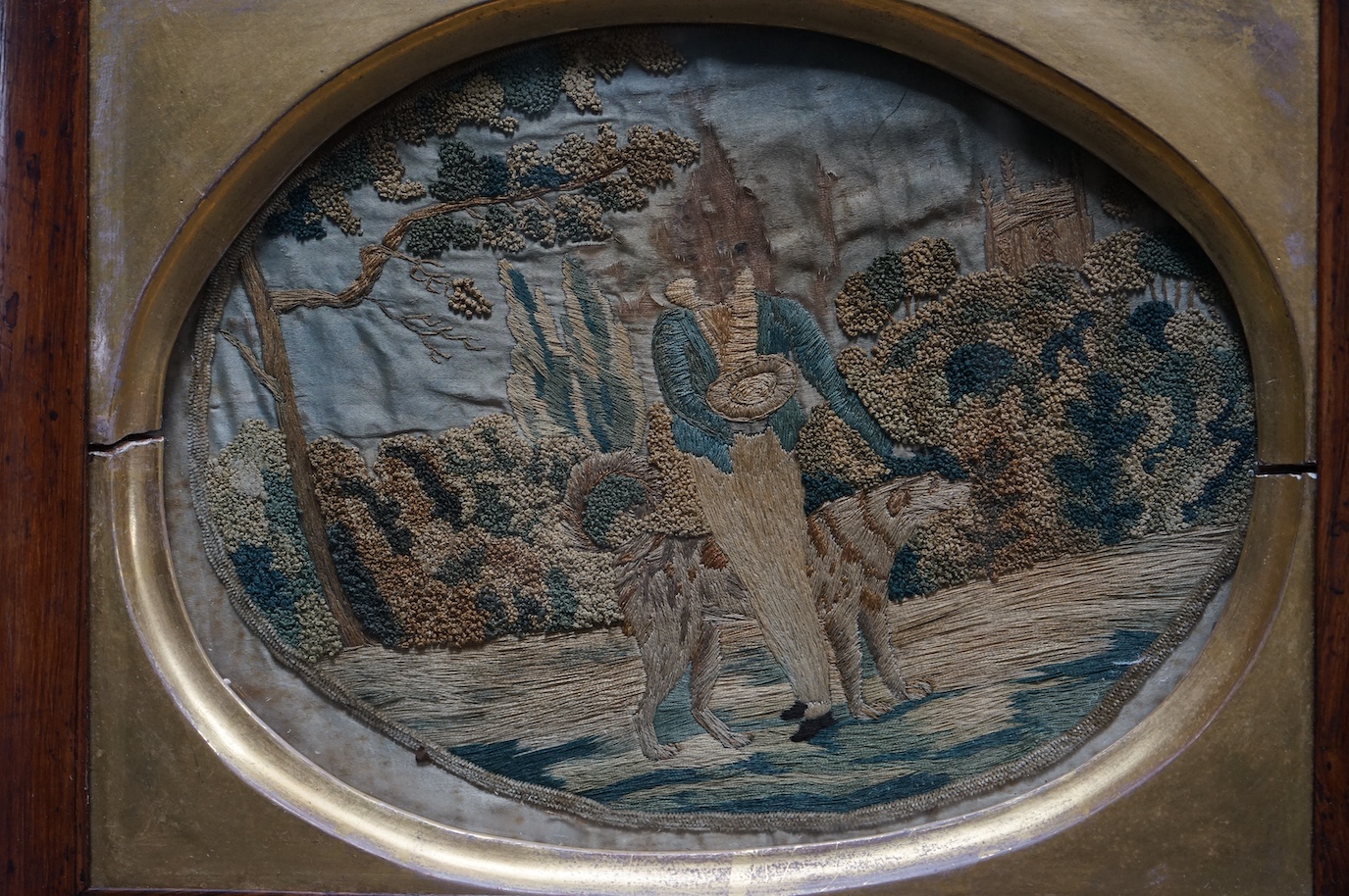 A pair of early 19th century rosewood-framed silk worked oval embroideries. Each embroidered with a boy and girl in a country landscape with their dogs. Worked in stem stitch and a knotting, the sky and faces hand painte